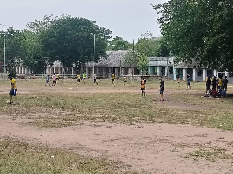 Students playing football on the open, uneven ground at Poonamallee Blind School